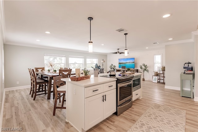 kitchen featuring white cabinetry, light wood-type flooring, a kitchen island, stainless steel range with electric cooktop, and pendant lighting