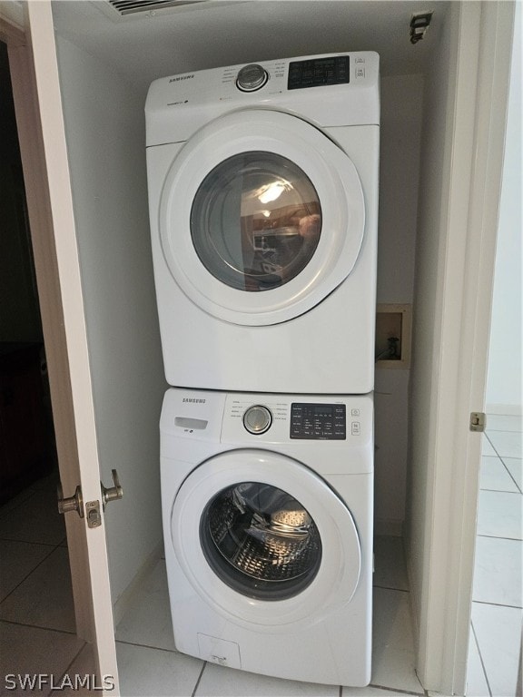 washroom featuring stacked washer and clothes dryer and light tile patterned floors