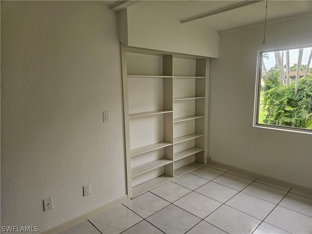 empty room featuring built in shelves and light tile patterned floors