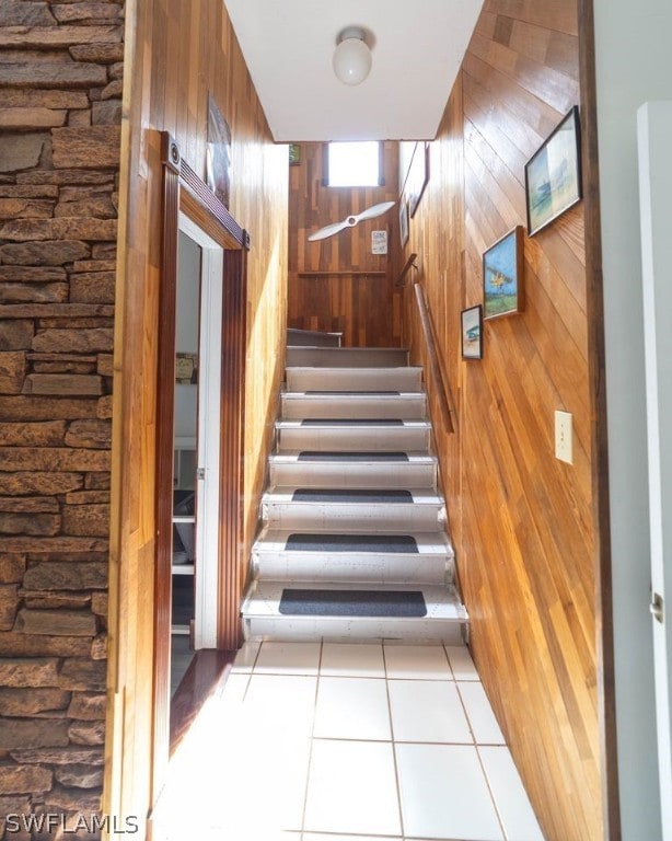 staircase featuring tile patterned flooring and wood walls