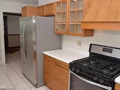 kitchen with light tile patterned floors, premium range hood, and stainless steel appliances