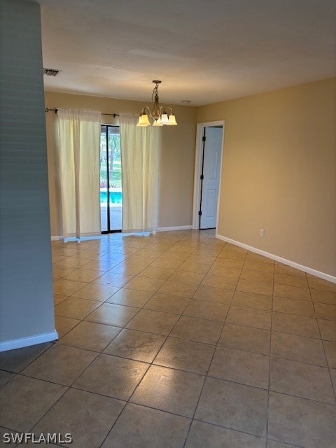 tiled empty room featuring a chandelier