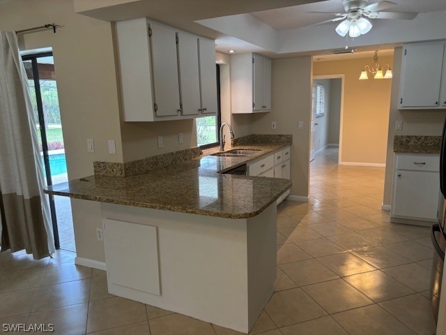 kitchen featuring kitchen peninsula, ceiling fan with notable chandelier, white cabinets, and light tile patterned floors