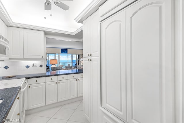 kitchen with light tile patterned floors, white appliances, ceiling fan, backsplash, and white cabinets