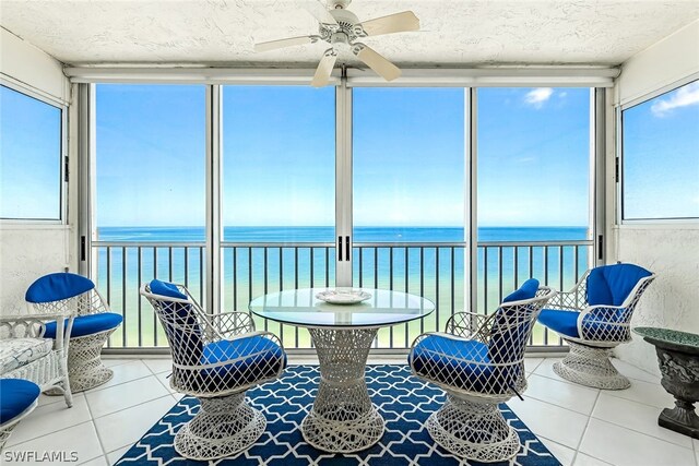 sunroom / solarium featuring ceiling fan and a water view