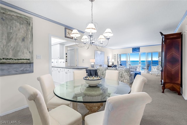 dining room with light carpet, baseboards, a chandelier, and ornamental molding