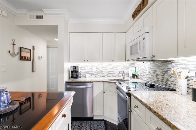 kitchen with appliances with stainless steel finishes, decorative backsplash, white cabinets, and light stone counters