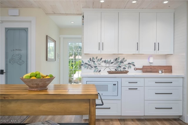 kitchen with tasteful backsplash, white cabinetry, and butcher block countertops