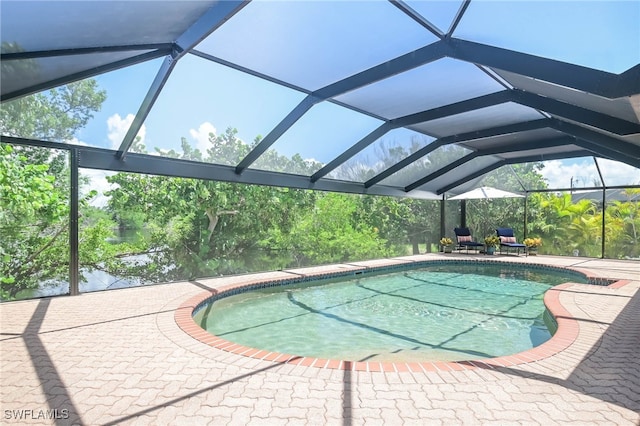 view of swimming pool featuring glass enclosure and a patio