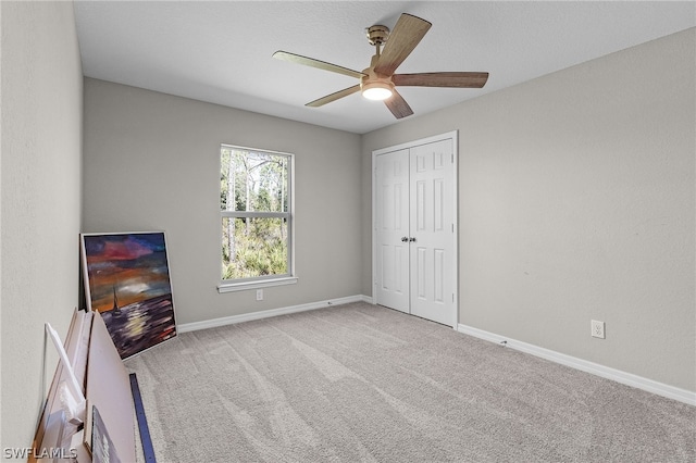 unfurnished bedroom with ceiling fan, light carpet, and a closet