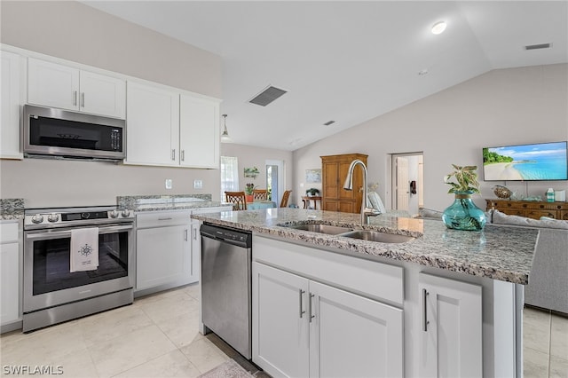 kitchen featuring appliances with stainless steel finishes, lofted ceiling, sink, white cabinets, and a center island with sink