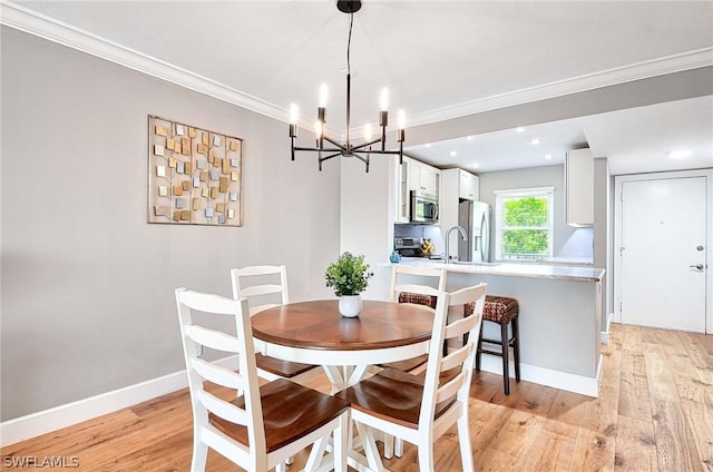 dining room with ornamental molding, sink, a notable chandelier, and light hardwood / wood-style flooring