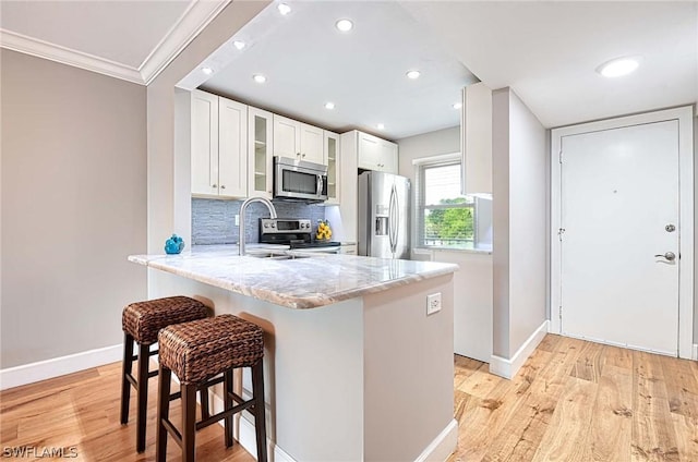 kitchen featuring white cabinetry, sink, a kitchen bar, kitchen peninsula, and stainless steel appliances