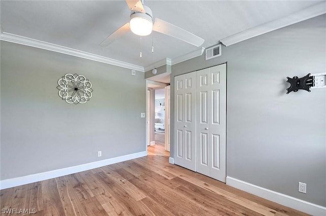 unfurnished bedroom featuring crown molding, a closet, ceiling fan, and light hardwood / wood-style flooring