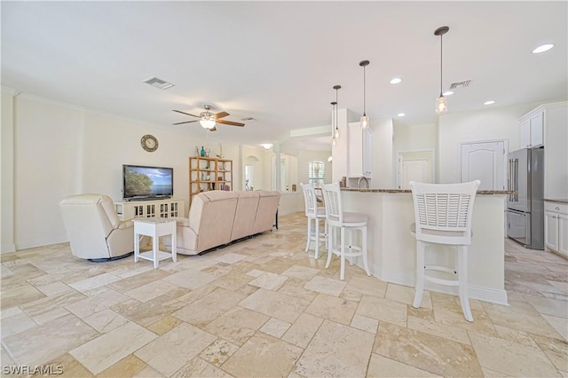 kitchen with ceiling fan, white cabinetry, hanging light fixtures, high quality fridge, and a kitchen bar