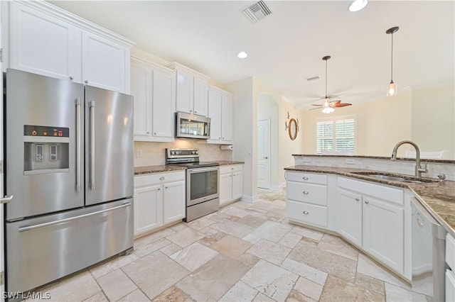 kitchen featuring sink, appliances with stainless steel finishes, white cabinetry, backsplash, and dark stone counters