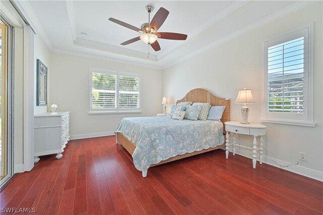 bedroom featuring dark wood-type flooring, ceiling fan, a tray ceiling, and crown molding