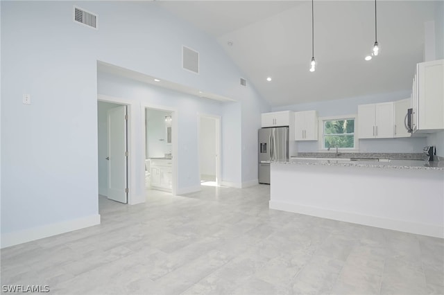 kitchen with light stone countertops, white cabinets, stainless steel appliances, hanging light fixtures, and high vaulted ceiling