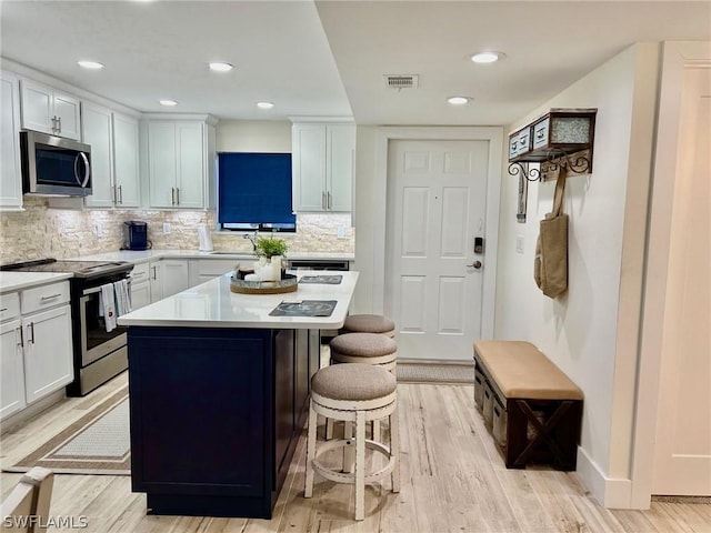 kitchen with appliances with stainless steel finishes, white cabinets, and a kitchen breakfast bar