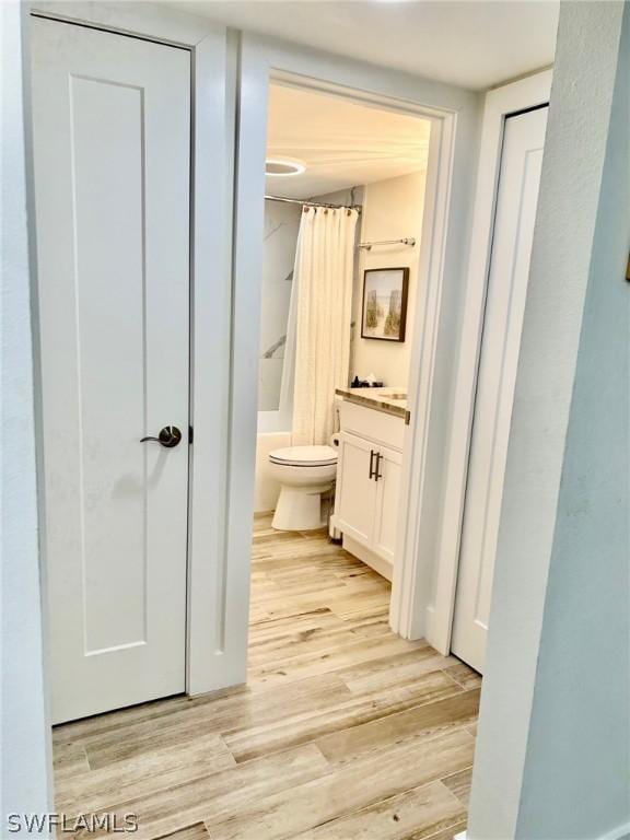 full bathroom featuring vanity, hardwood / wood-style floors, shower / bath combo, and toilet