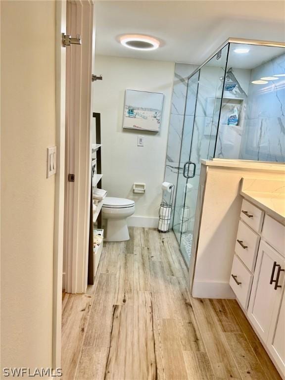 bathroom featuring a shower with door, wood-type flooring, vanity, and toilet