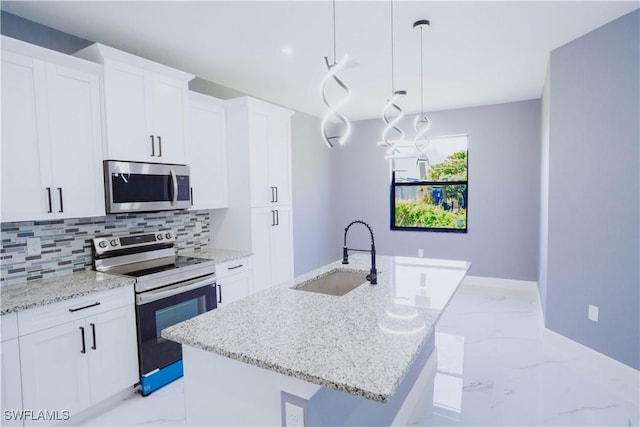 kitchen with pendant lighting, sink, a kitchen island with sink, stainless steel appliances, and white cabinets