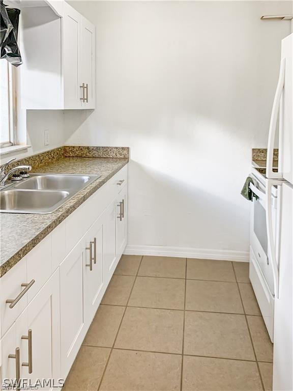 kitchen featuring light tile patterned floors, sink, and white cabinets