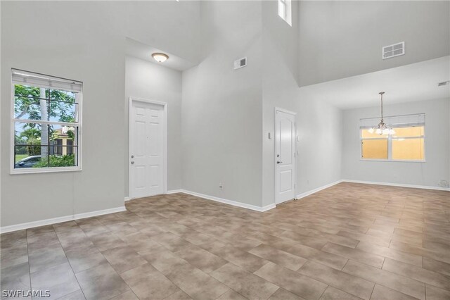 unfurnished room featuring a towering ceiling and a notable chandelier