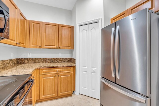 kitchen featuring appliances with stainless steel finishes, light stone countertops, and light tile patterned floors