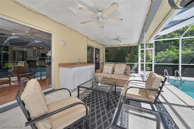 view of patio with ceiling fan, an outdoor hangout area, sink, and glass enclosure