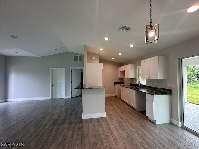 kitchen with white cabinetry, visible vents, open floor plan, and a sink