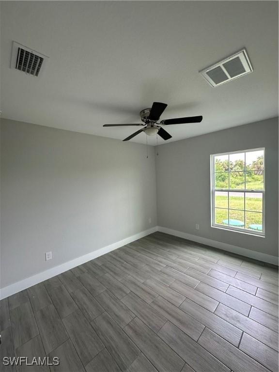 spare room featuring ceiling fan, wood tiled floor, visible vents, and baseboards