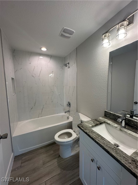 full bathroom featuring tiled shower / bath, toilet, a textured ceiling, and vanity