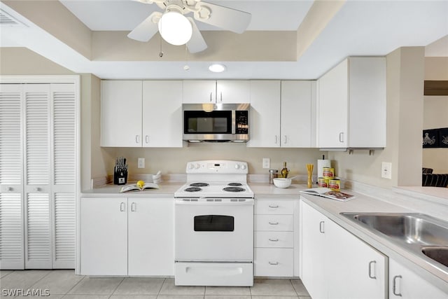 kitchen featuring white electric range, sink, white cabinets, light tile patterned floors, and a raised ceiling