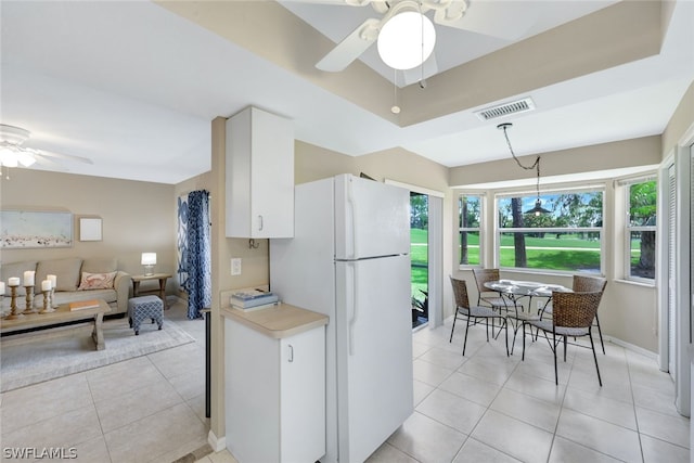 kitchen with white refrigerator, white cabinets, ceiling fan, and light tile patterned floors