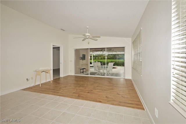 spare room featuring a ceiling fan, lofted ceiling, and light tile patterned floors