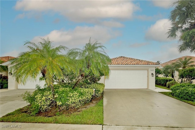 view of front of home with a garage, a tiled roof, concrete driveway, and stucco siding