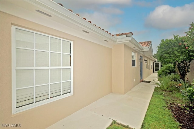 view of property exterior featuring a patio area, a tiled roof, and stucco siding