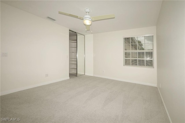 empty room with carpet floors, visible vents, ceiling fan, and baseboards