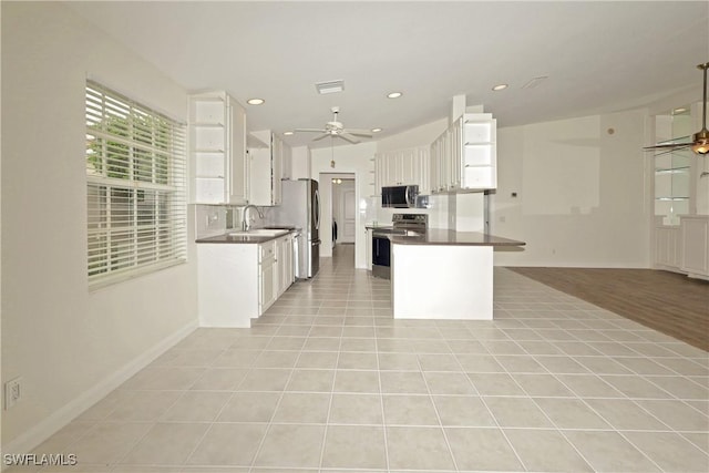 kitchen with white cabinets, dark countertops, stainless steel appliances, and light tile patterned flooring