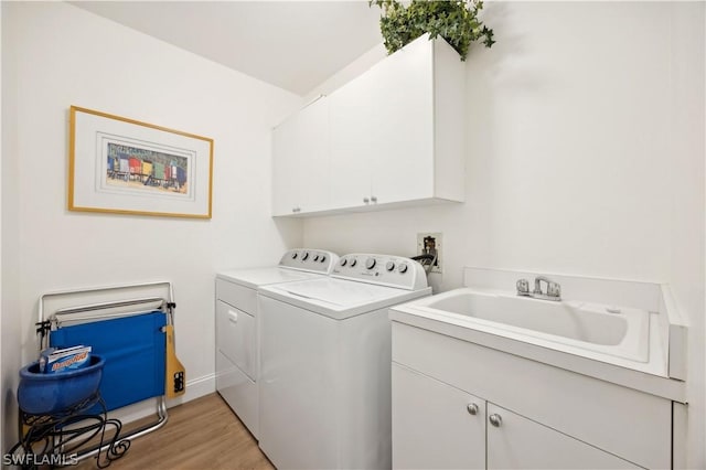 washroom featuring light hardwood / wood-style floors, sink, washing machine and dryer, and cabinets