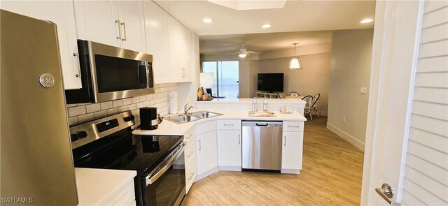 kitchen featuring backsplash, white cabinets, sink, kitchen peninsula, and stainless steel appliances