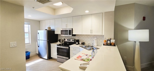 kitchen featuring white cabinets, sink, light wood-type flooring, tasteful backsplash, and stainless steel appliances