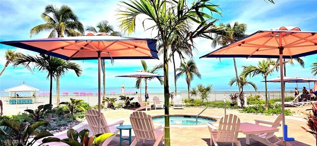 view of swimming pool featuring a water view, a patio, and a hot tub