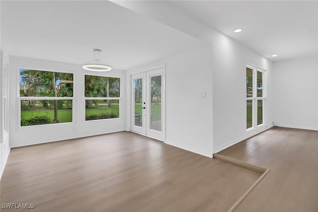 unfurnished room with hardwood / wood-style floors, french doors, and a healthy amount of sunlight