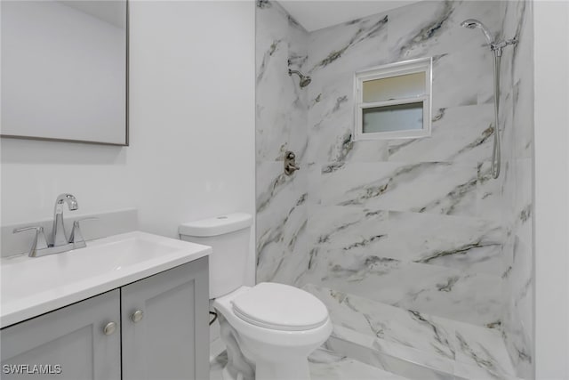 bathroom with a tile shower, vanity, and toilet