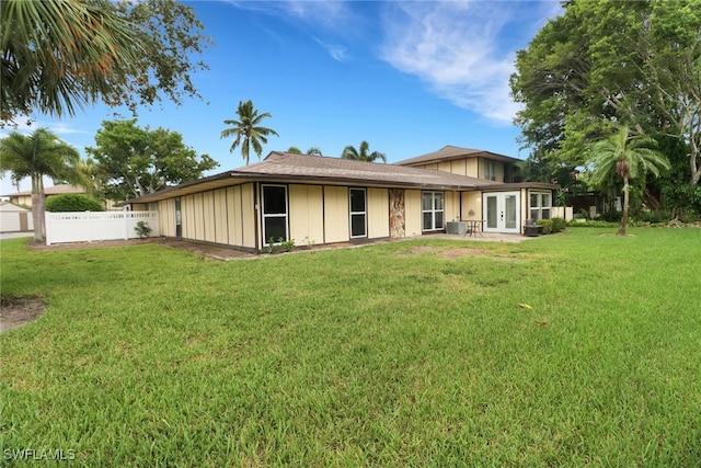 rear view of property featuring a lawn and central AC unit