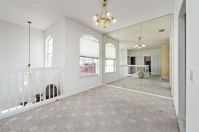 carpeted spare room featuring a notable chandelier