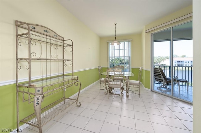 dining room featuring a water view, tile patterned floors, and vaulted ceiling