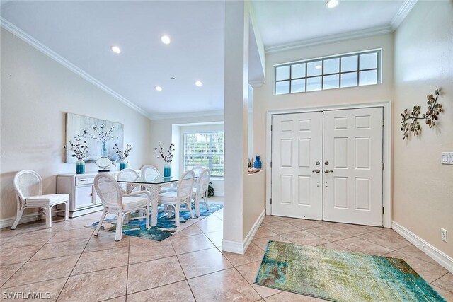 tiled foyer featuring crown molding and high vaulted ceiling